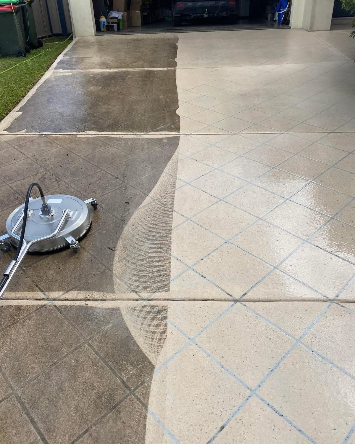Concrete driveway being cleaned with pressure washer, showing before and after sections